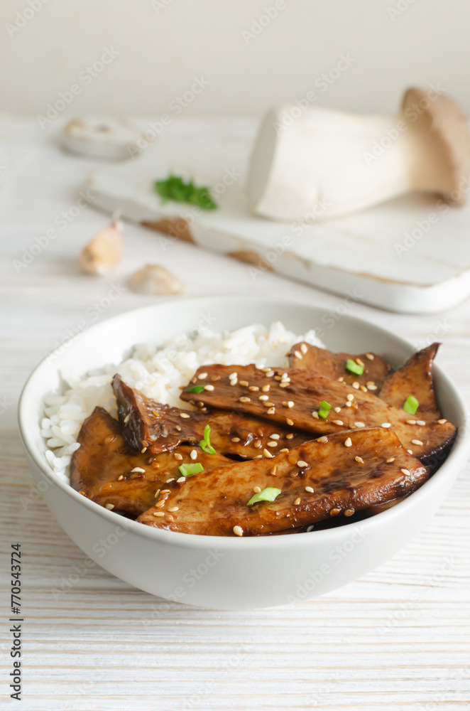 Eryngii mushroom fried with sesame and green onion and white boiled rice in a gray bowl. Dishes Gochujang King Oyster Mushrooms. Traditional Korean cuisine. Vertical orientation. Eryngii mushroom fried with sesame and green onion and white boiled rice in a gray bowl. Dishes Gochujang King Oyster Mushrooms. Traditional Korean cuisine. Vertical orientation.