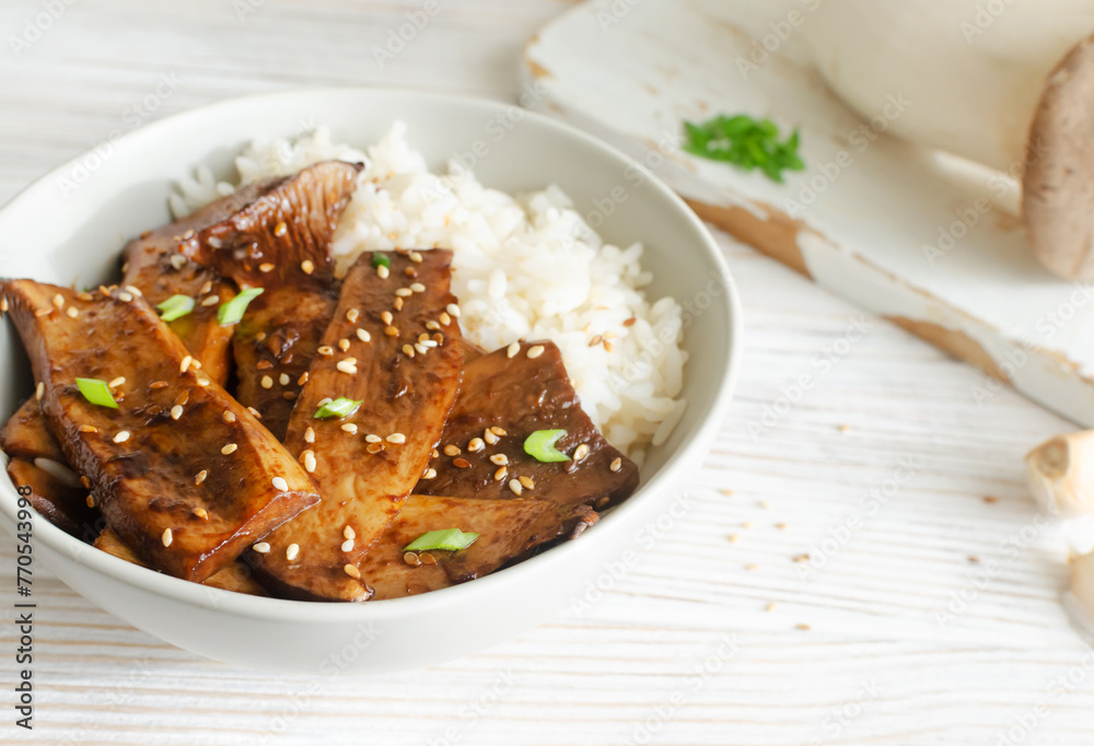 Eryngii mushroom fried with sesame and green onion and white boiled rice in a gray bowl. Dishes Gochujang King Oyster Mushrooms. Traditional Korean cuisine. Horizontal orientation. Eryngii mushroom fried with sesame and green onion and white boiled rice in a gray bowl. Dishes Gochujang King Oyster Mushrooms. Traditional Korean cuisine. Horizontal orientation.