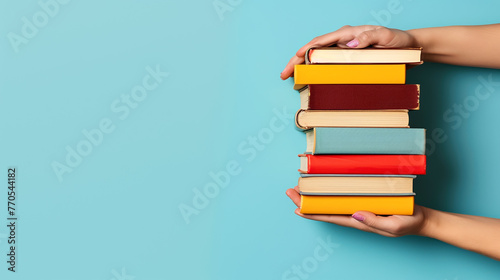 A woman's hand holding a stack of books against a blue background