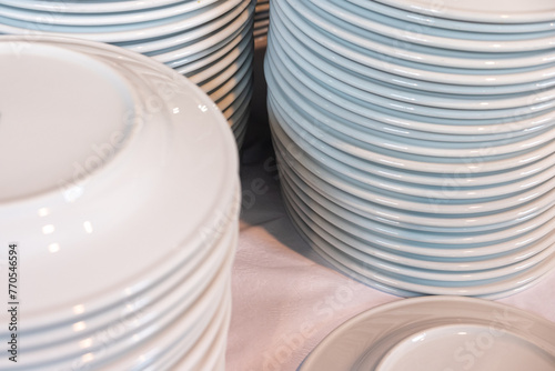 many white ceramic dishes piled up after washing