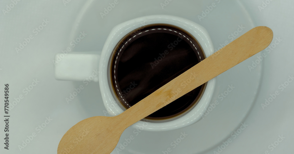 Kawa w maleńkiej filiżance  z drewnianą małą łyżeczką. Świeżo parzona kawa espresso ,wciąż parująca, z małą drewnianą "eko" łyżeczką umieszczoną na filiżance. - obrazy, fototapety, plakaty 