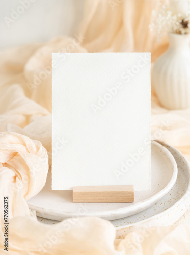 Vertical card near cream tulle fabric on plates close up, copy space, wedding stationery mockup