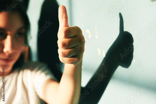 Latin preteen girl showing thumb up. Shadow on the wall.
