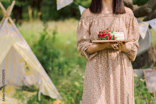 girl holding a raspberry cake in the garden.