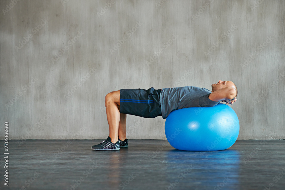 Naklejka premium Man, fitness and stretching with exercise ball for workout, training or balance at gym. Active male person lying on round object, equipment or support for warm up, health and wellness on mockup space