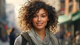 portrait of a smiling mixed race woman with beautiful eyes. brown curly hair. blurred city background. copy space.