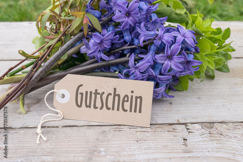 Bouquet of blue hyacinths and card with German text: Voucher