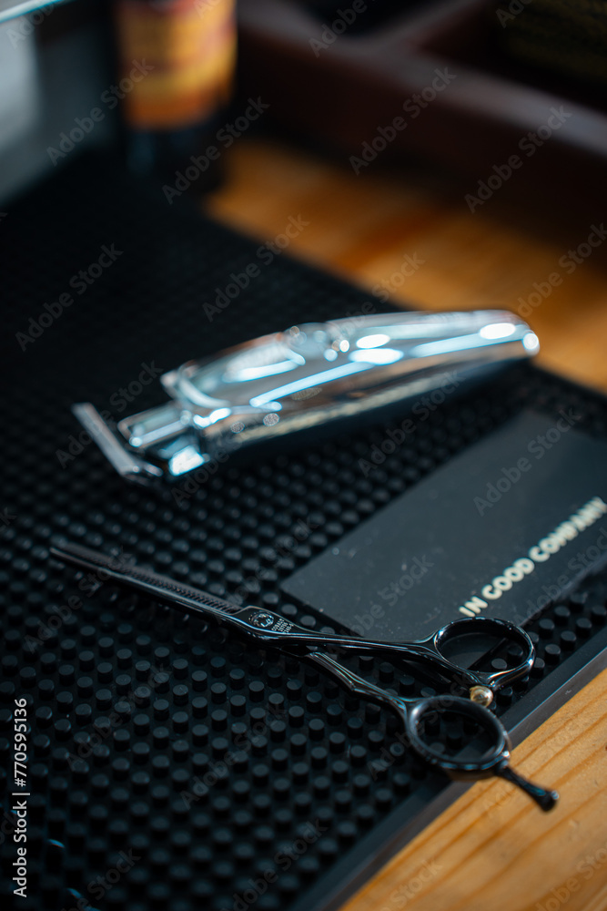 Scissor and clipper in barbeshop on dark rubber background Scissor and clipper in barbeshop on dark rubber background