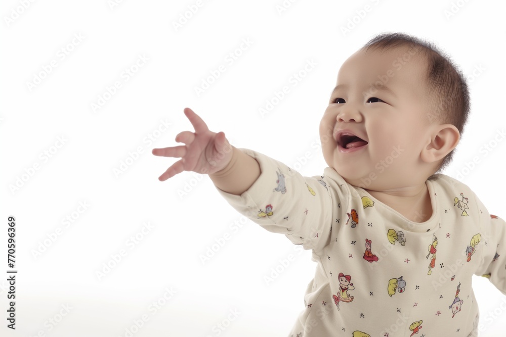 A giggling baby raises an arm in delight, wearing a white t shirt against a white backdrop A giggling baby raises an arm in delight, wearing a white t shirt against a white backdrop
