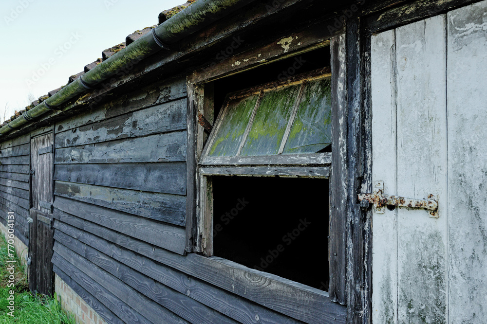 Derelict horse stable and wooden outbuildings seen on an old English dairy farm in the UK. A horse stable door can be seen in the background. - obrazy, fototapety, plakaty 