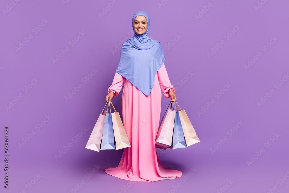 Full body photo of funny millennial lady do shopping wearing blue arabic head wrap muslim pink dress isolated over violet color background