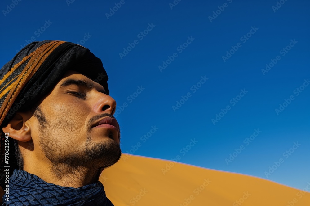 arabian man with closed eyes on a dune under the clear blue sky arabian man with closed eyes on a dune under the clear blue sky