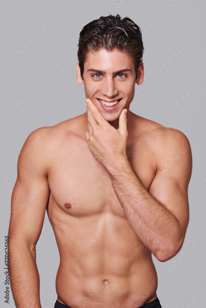 Man, skincare and smile in studio portrait with hand on face for wellness by gray background. Person, model and facial dermatology for self care, health or transformation for happy, pride or results Man, skincare and smile in studio portrait with hand on face for wellness by gray background. Person, model and facial dermatology for self care, health or transformation for happy, pride or results