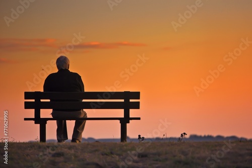 elderly man on bench, profile facing orangehued horizon