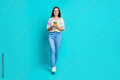 Photo of charming cute pretty woman blogger addicted user wear trendy print clothes go store isolated on cyan color background