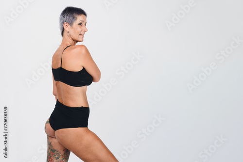 attractive short haired adult woman in black underwear posing, studio shot with white background