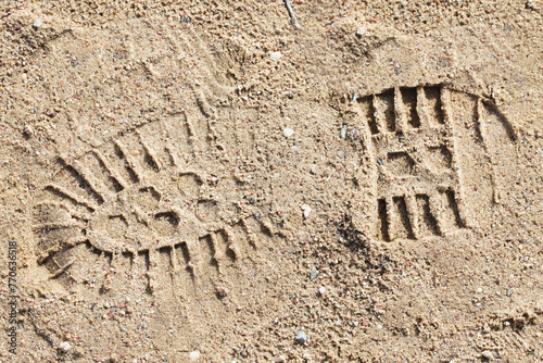 Shoe imprint in sand. Wet sand beach. Trekking shoes print. Walking on sand. Tracking person trail marks background.