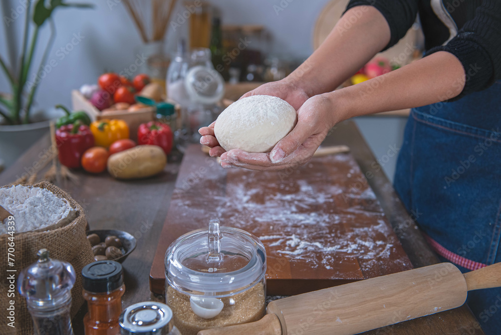 Woman uses hands to knead pizza dough, prepares and rests the pizza dough before putting it in the oven. To the kitchen concept and homemade pizza