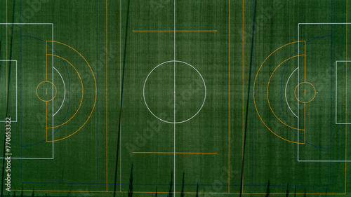 An aerial view looking down at a green soccer field at sunrise