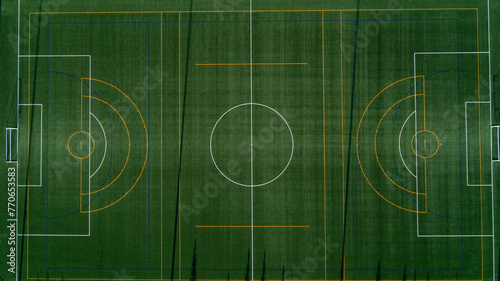 An aerial view looking down at a green soccer field at sunrise