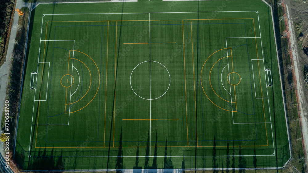 An aerial view of a green soccer field with lights and a path around it at sunrise An aerial view of a green soccer field with lights and a path around it at sunrise