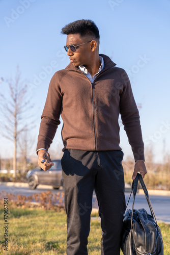 Canvas Print A man wearing a brown jacket and black pants is holding a black bag