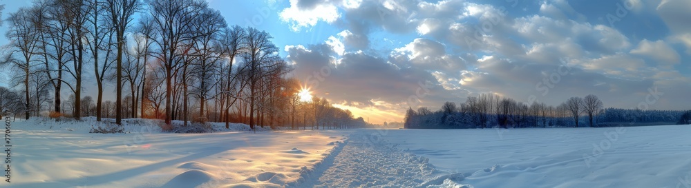 A snowy field with trees in the background and a beautiful sunset in the sky