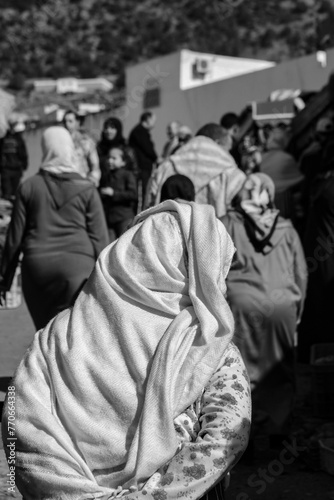 Greyscale vertical image of women in hijabs strolling down the street