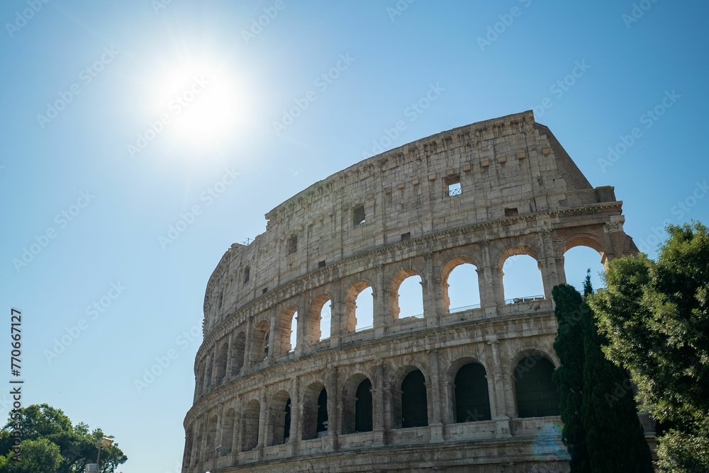 Low angle shot of the Colosseum under a blue sky and sunlight in Rome, Italy