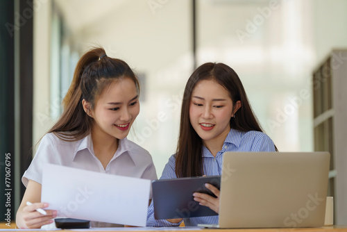 Two Asian businesswomen discuss new startup project idea presentation and analyze planning and financial statistics and investment market at the office.