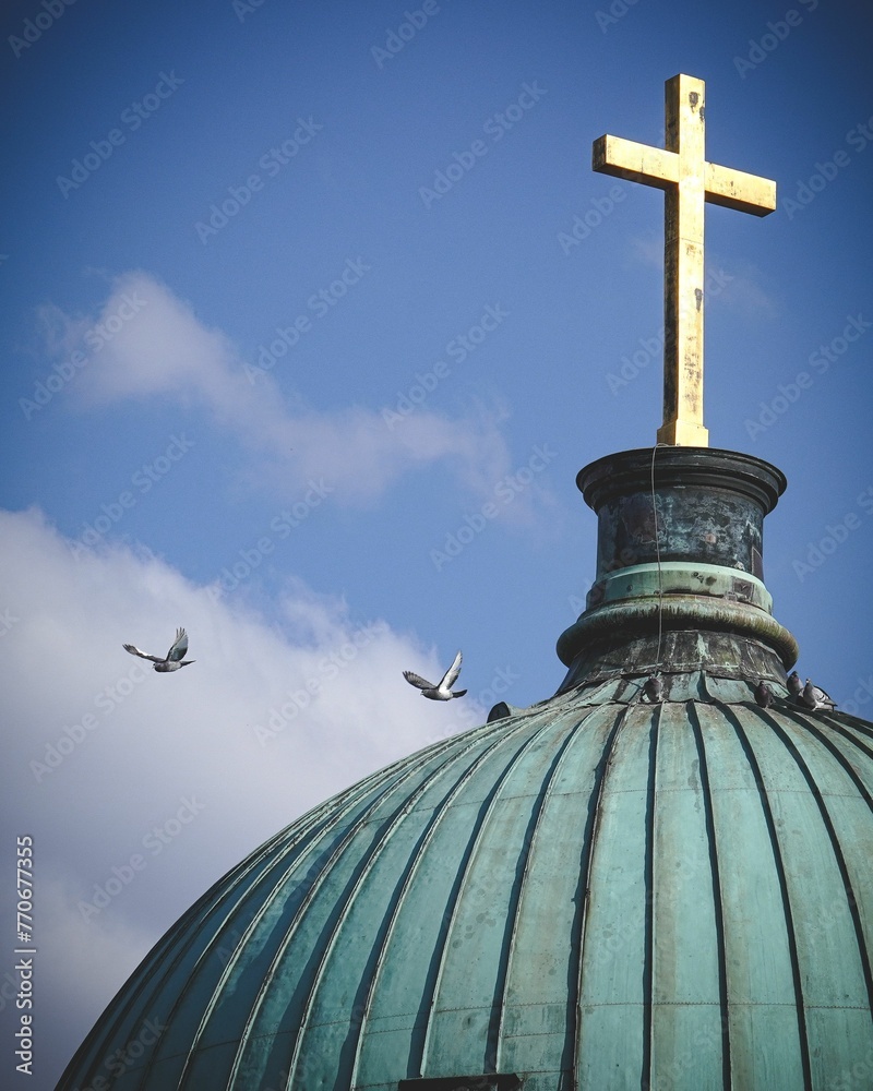 an airplane flying in the sky above a dome with a cross on top