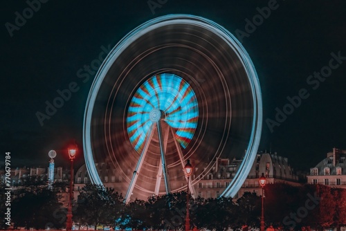 Long exposure shot of an illuminated Ferris wheel against a night sky in a park.