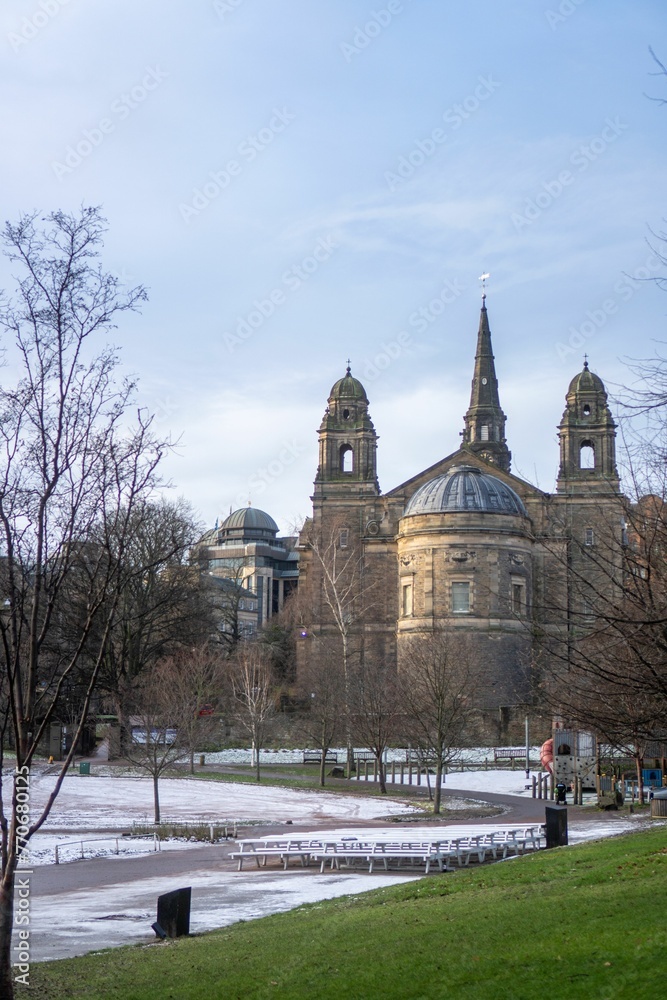 Obraz premium a bench in a park in front of some large buildings