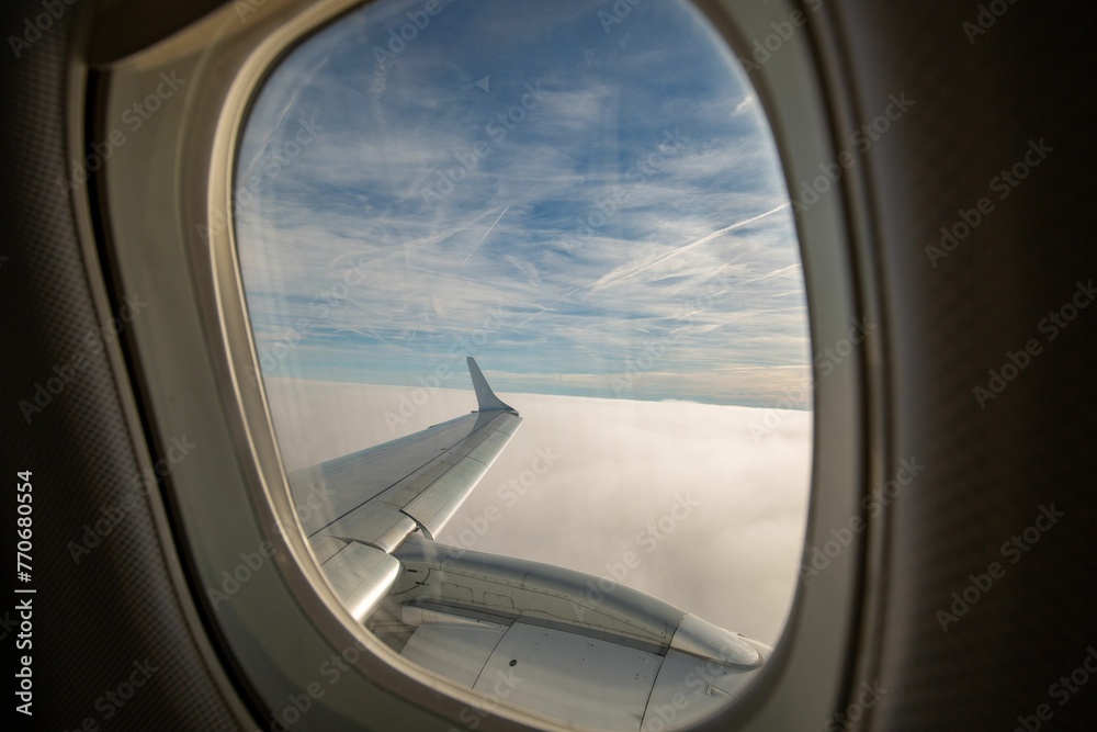 Airplane wing with clouds in the background seen through a window Airplane wing with clouds in the background seen through a window
