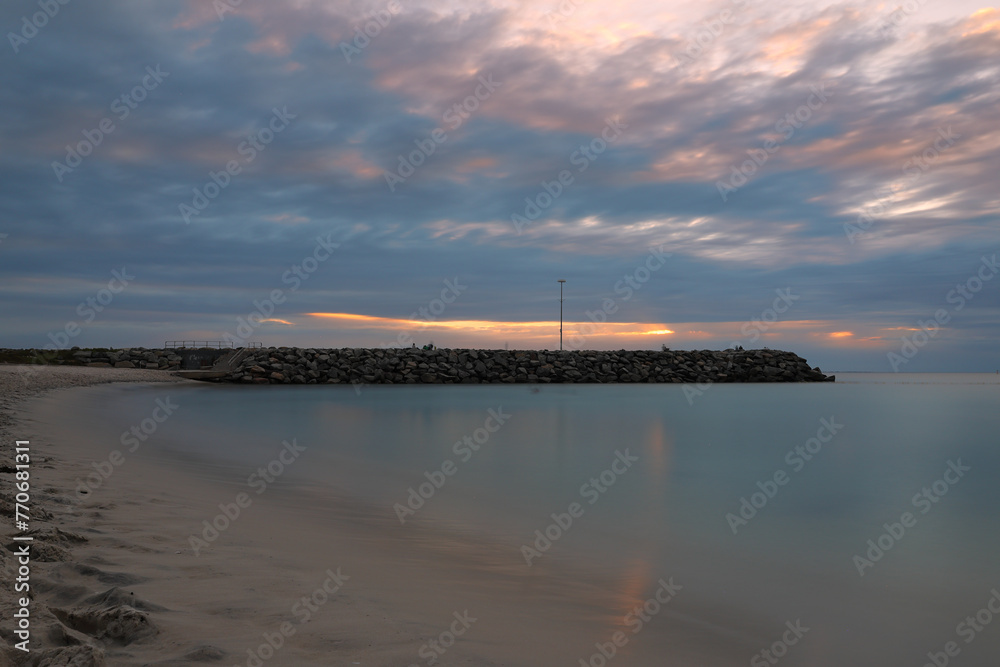 Long exposure photograph at sunset of the ocean and rock wall groyne at Cottesloe Beach, Perth, Western Australia - obrazy, fototapety, plakaty 