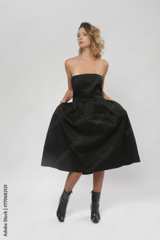 Fototapeta premium Serie of studio photos of female model in black tube top A line midi dress 