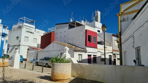 Village of Alvor in Portugal with vintage buildings and cars parked in the cobblestone streets