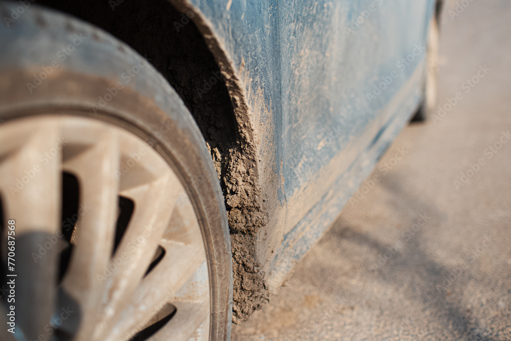 Close-up of dirty car wheel on the asphalting road.