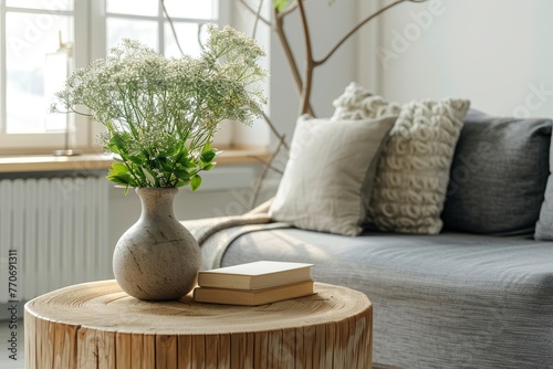Simple decoration in a light living room. A vase with flowers on a small wooden table. Modern interior.