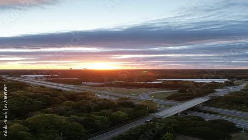 Time lapse drone footage of the clouds moving in the dusk sky over the cars driving on roads photo