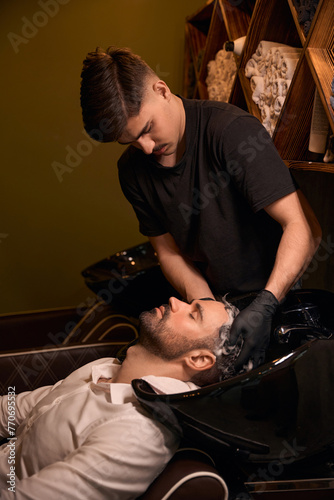 Hairdresser man washing client head with shampoo
