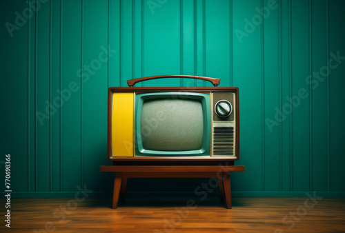 An old-style TV set sits on a wooden floor, its dark yellow and teal colors and bold and playful nature apparent.