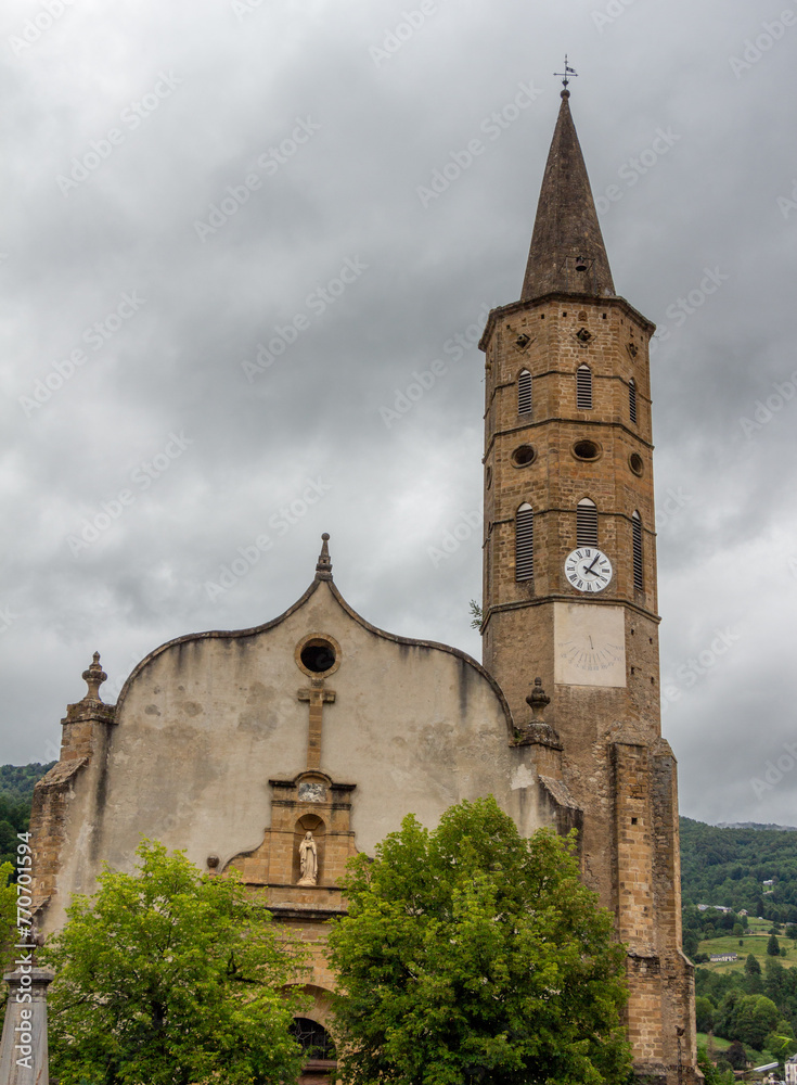 View of the tower of the church of Massat, Ariège, Occitanie, France. Village houses.