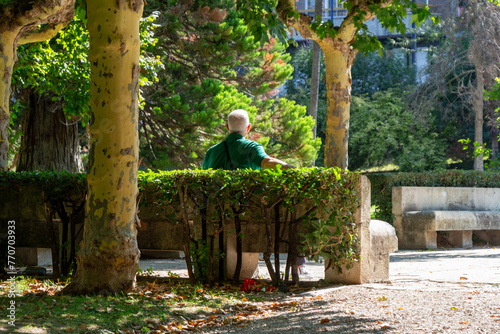 Man from behind sitting on a bench in the Parque de las Moreras in Valladolid, Spain. English : Moreras Park. White hair.