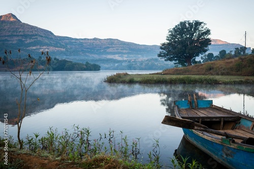 Beautiful landscape with a boat of a lake, hills, and valleys at Arthur Lake in Bhandardara, India