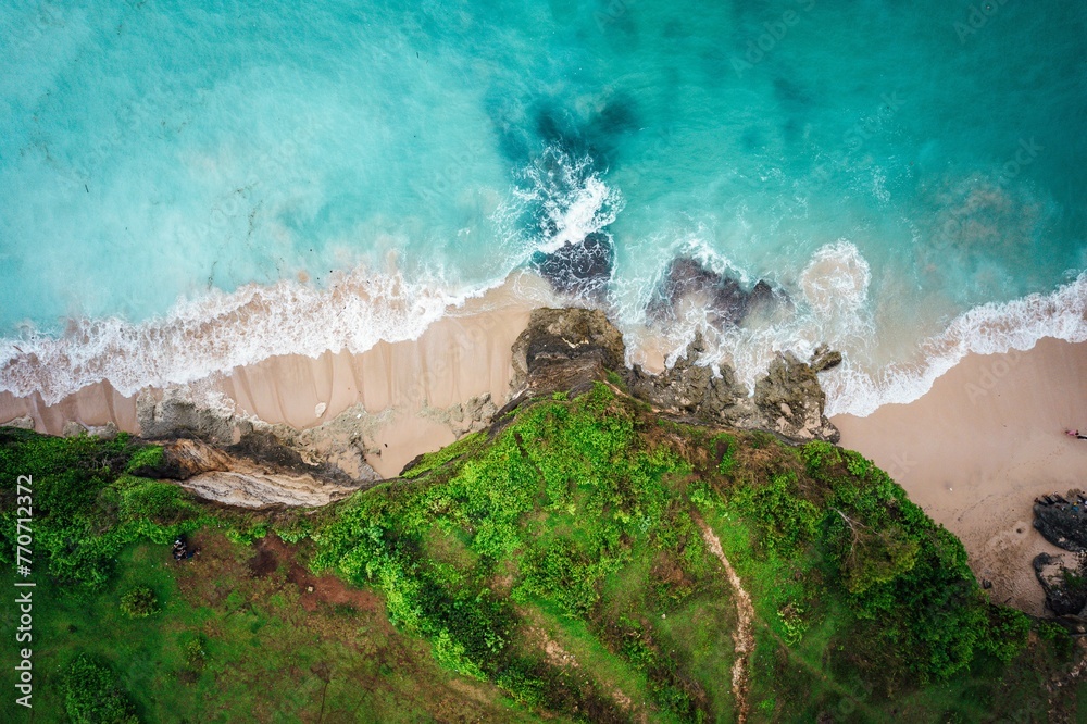 Aerial view of a paradise-like beach with white sand and turquoise-colored waves lapping up