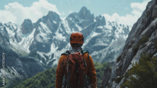 A mountaineer, equipped with climbing gear, stands before a towering rock formation in the mountainous wilderness.