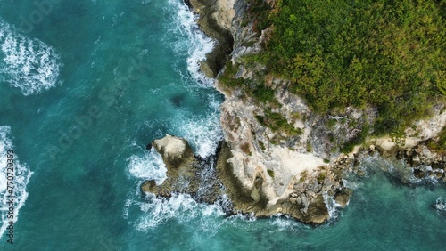 Aerial view of a stunning beach with rocky cliffs with waves crashing on the rocks