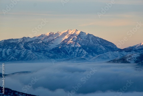 the snow capped mountains with thick clouds are pictured at sunset