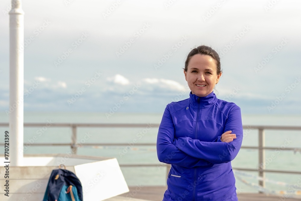 Young woman standing with arms crossed in front of her against a backdrop of the vast ocean Young woman standing with arms crossed in front of her against a backdrop of the vast ocean